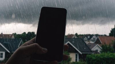 Celular na mão com tempestade ao fundo